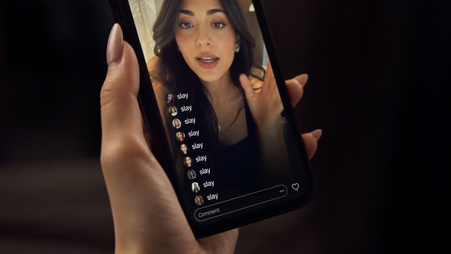 A phone held in a hand with manicured nails plays a vertical video of a creator talking to camera; the comment feed overlaid on the left shows a column of different users all posting the same single word.